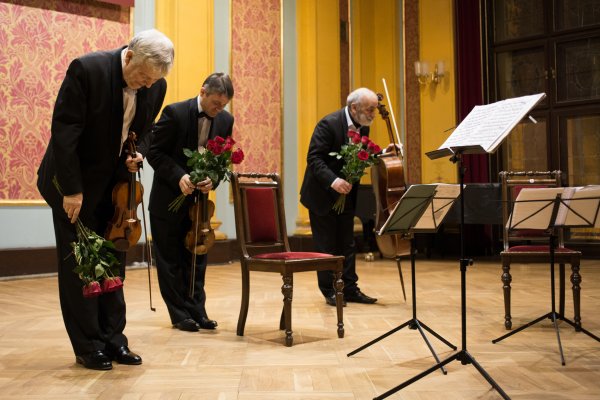 na scenie trzej mężczyźni kłaniają się trzymając w dłoniach bukiety z czerwonych róż
