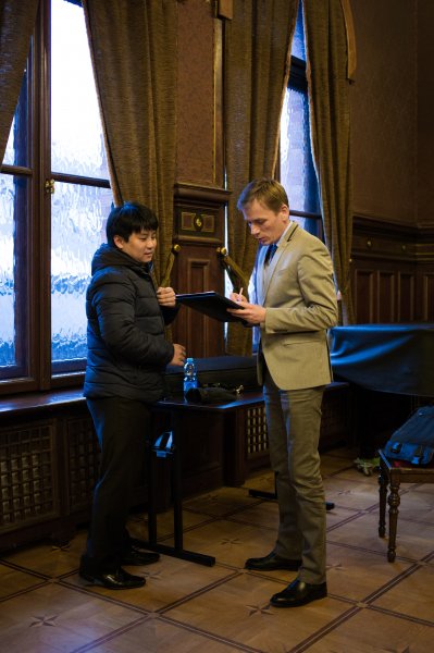 dwaj mężczyźni rozmawiają ze sobą, jeden spogląda w teczkę