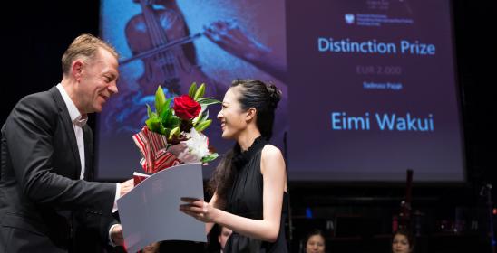 Mężczyzna wręcza młodej kobiecie dyplom i bukiet kwiatów