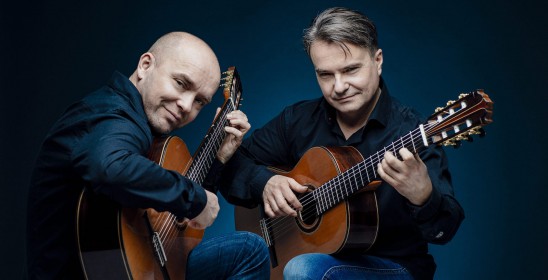 dwóch mężczyzn grających na gitarach