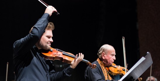 dwóch mężczyzn grających na skrzypcach