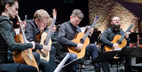 kobieta i troje mężczyzn grających na gitarach
