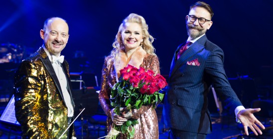 dwóch mężczyzn i kobieta trzymająca bukiet czerwonych róż