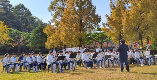 młodzieć siedząca w parku dla na instrumentach, przed nimi stoi dyrygent