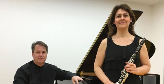 mężczyzna iedzący przy fortepianie i kobieta trzymająca klarnet