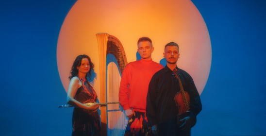 kobieta i dwóch mężczyzz na tle pomarańczowego koła