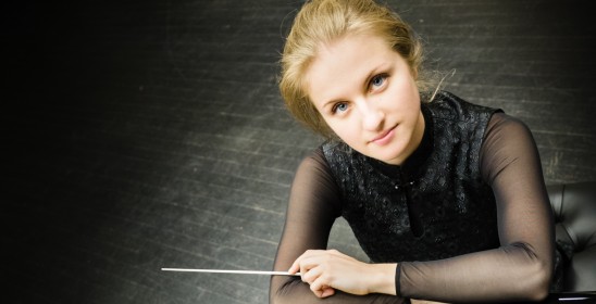 portret kobiety opierającej się o fortepian i trzymającej w jednej ręce batutę