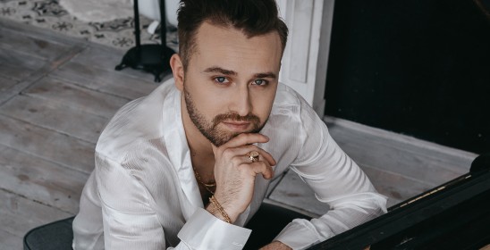 mężczyzna w białej koszuli siedzi przy fortepianie