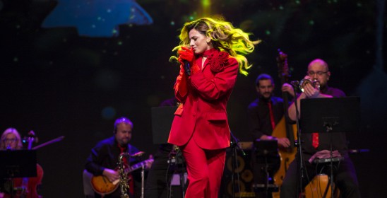 kobieta w czerwonym garniturze śpiewa do mikrofonu