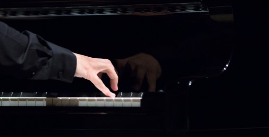 dłoń trzymana nad klawiaturą fortepianu