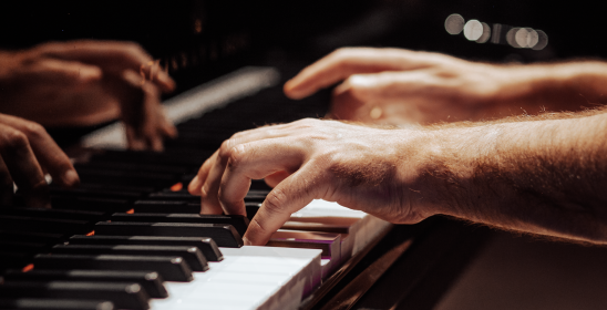 dłonie leżące na klawiaturze fortepianu
