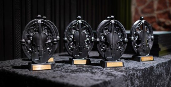 Na zdjęciu przedstawione są cztery statuetki Muzy TOS-u, które stoją na stole pokrytym czarną tkaniną.