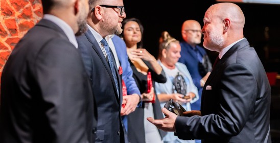 prezydent Torunia i dyrektor orkiestry wręczają statuetkę muzę TOS-u grafikowi Jarosławowi Pawlickiemu