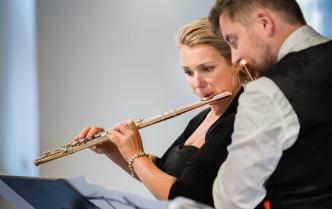 Kobieta i mężczyzna ze skupionymi twarzami patrząc w nuty grają na fletach