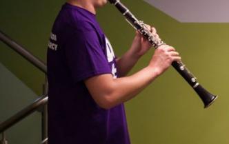 młody mężczyzna gra na klarnecie na klatce schodowej