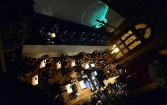 artyści na scenie, za nimi projekcja, przytłumione światło, widok z góry