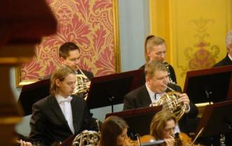 trzech mężczyzn grających na waltorniach oraz klarnecistka