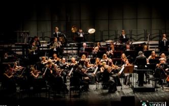 muzycy na scenie w centrum perkusista z rozłożonymi szeroko rękoma z talerzami