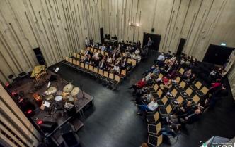 scena z podestów, na niej instrumenty, dalej widzowie na krzesłach, zdjęcie robione z góry