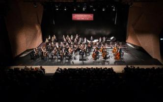 orkiestra stoi na scenie, za nimi wisi baner z nazwą festiwalu
