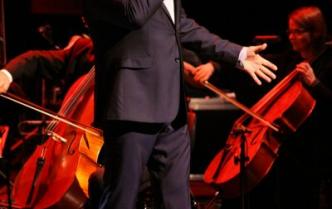 mężczyzna w garniturze stoi na scenie z mikrofonem w dłoni