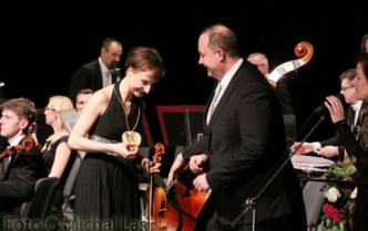 kobieta ze skrzypcami w rękach odbierająca medal