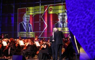 orkiestra na scenie, za nimi wyświetlony komiks z oficjelami