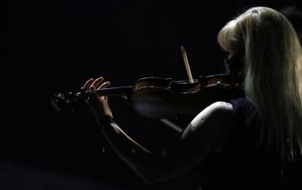 kobieta z długimi włosami opadającymi na plecach gra na skrzypcach