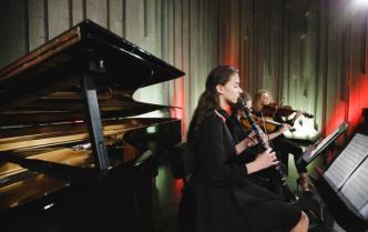 Trzy kobiety grają siedząc obok siebie - Zuzanna Lasek gra na klarnecie, Kinga Politowska gra na skrzypcach i Anna Morawska gra na altówce przed nimi stoją pulpity z nutami 
