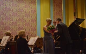 solistka w niebieskiej sukni z kwiatami na scenie obok fortepian