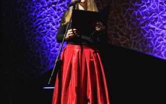 kobieta w czerwonej spódnicy mówiąca do mikrofonu