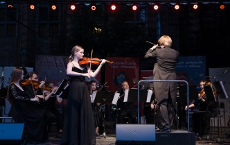 kobieta grająca na skrzypcach i dyrygent odwrócony plecami