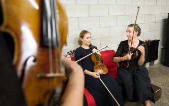 two seated women holding a violin in their hands