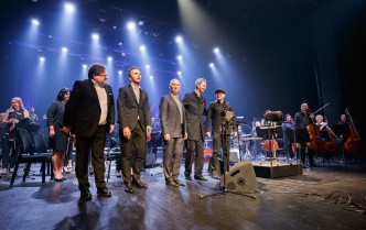 pięcioro mężczyzn stojących w rzędzie na scenie