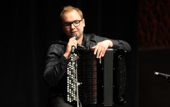 a man holding an accordion is talking into the microphone