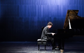 mężczyzna w ciemnym garniturze gra na fortepianie