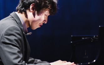 młody mężczyzna ze skupioną twarzą gra na fortepianie