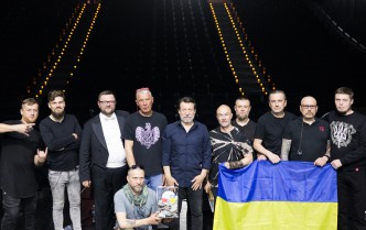 grupa mężczyzn stojąca na scenie i trzymająca flagę Ukrainy