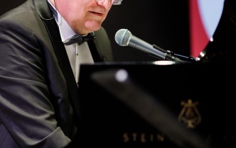 zbliżenie na mężczyznę grającego przy fortepianie, mającego przed sobą mikrofon
