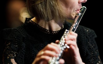 zbliżenie na kobietę w czarnym stroju grającą na flecie