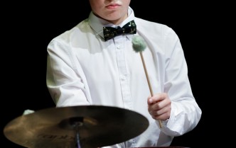 zbliżenie na chłopaka w białej koszuli grającego na instrumentach perkusyjnych
