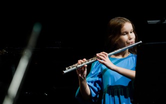 zbliżenie na dziewczynkę w niebieskim stroju grającą na flecie
