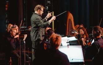 dyrygent z uniesionymi rękoma i orkiesta