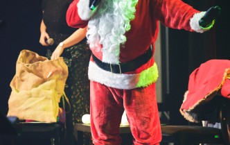mężczyzna w stroju świętego Mikołaja przemawiający na scenie