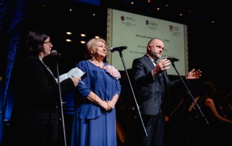 dwie kobiety i mężczyzna stoją przy mikrofonach