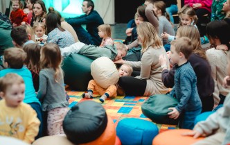 dorośli i dzieci siedzący na kolorowym dywanie