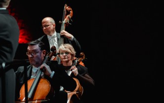 mężczyzna i kobieta grają na wiolonczelach, za nimi mężczyzna gra na kontrabasie