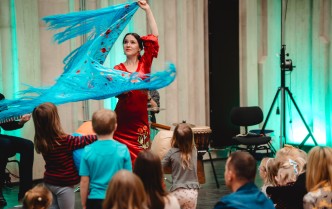 kobieta w czerwonej sukni tańczy trzymając dużą, niebieską chustę