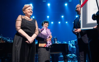 dwie kobiety w czarnych sukniach, jedna trzyma bukiet kolorowych kwiatów