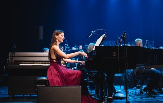 kobieta w czerwonej sukni gra na fortepianie